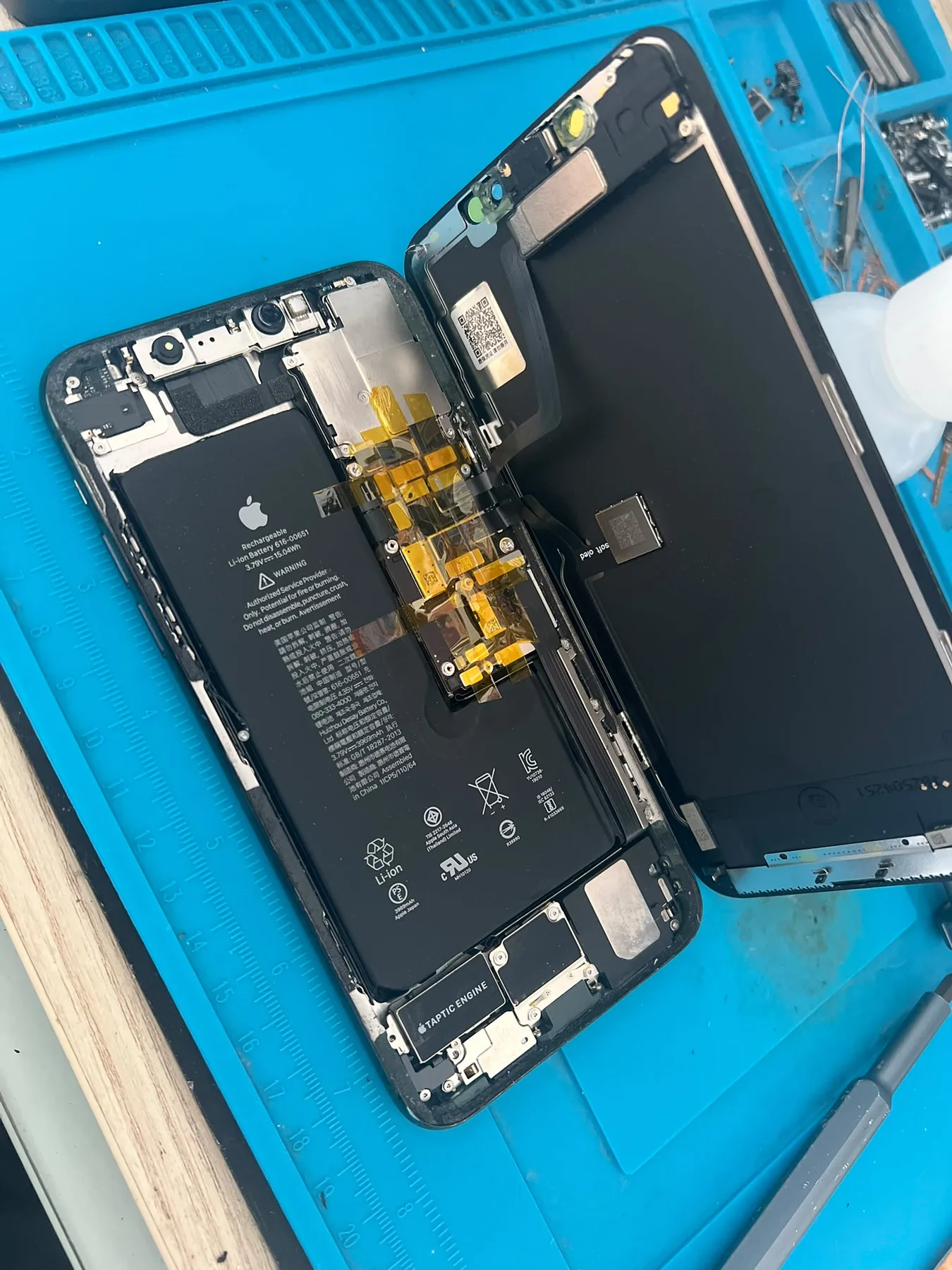 Photo réelle d’un iPhone ouvert montrant sa batterie pendant une réparation chez Badiphone à Lille.