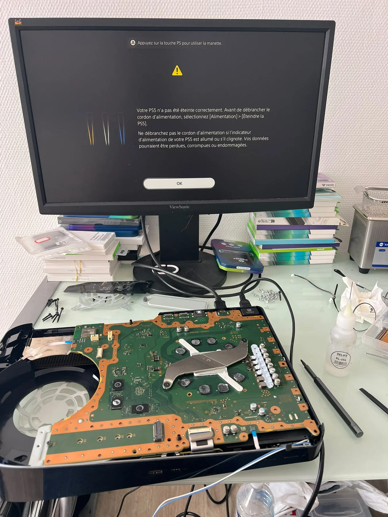 Photo réelle d’une PS5 démontée avec sa carte mère en cours de diagnostic chez Badiphone à Lille.